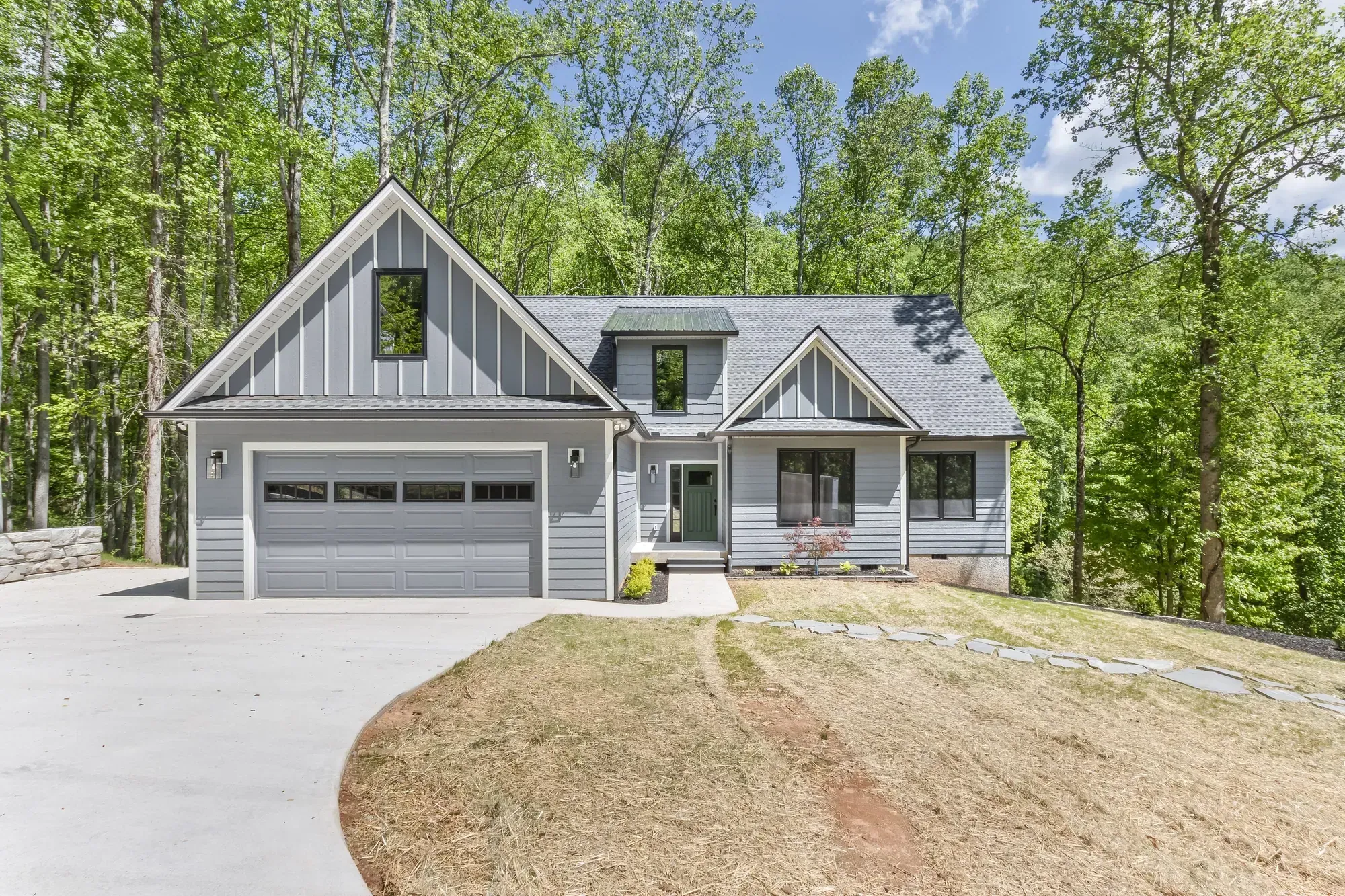 New custom home with gray lap siding, board-and-batten gables and a two-car garage in Candler, NC, built by Buckingham Builders